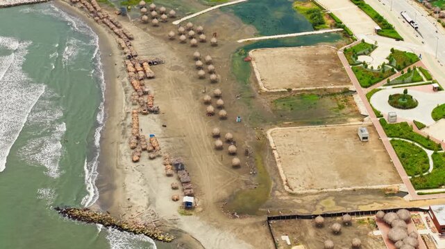 High aerial view of waves crashing on the sandy shore of puerto colombia with straw umbrellas