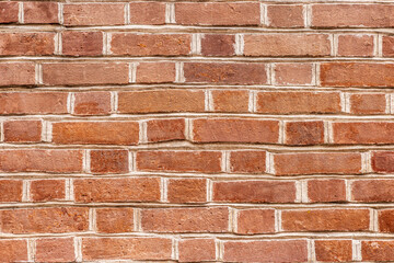 A close-up view of a red brick wall with a uniform pattern. The bricks are arranged in a classic horizontal layout, showcasing their texture and color.