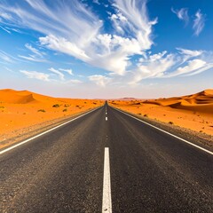 Straight road through orange desert dunes, dramatic sky