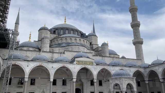 Tour the stunning exterior of the Blue Mosque in Istanbul Turkey as the cloudy sky sets a dramatic backdrop. Experience the beauty of its domes and minarets in this captivating location