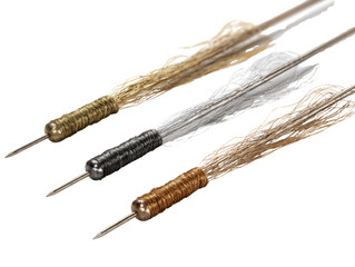 Three ornamental needle-like tools with metallic thread handles and flowing, wispy strands. Features antique gold, silver, and copper designs. background removed