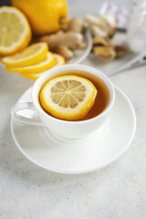 Cold and flu season treatment still life with cup of tea, lemon, pills, thermometer, nasal sprays, garlic and ginger, health and wellness concept