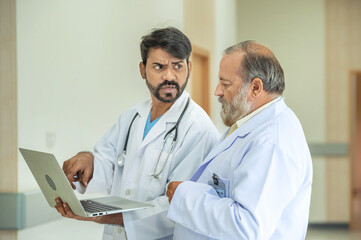 Two senior doctor hold clipboard document file of patient record talking discussion about treatment guidelines. Men surgeon doctor advice assistance expertise for comprehensive care team.