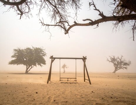 Lonely swing set in a hazy, sandy, deserted landscape