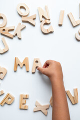 Child hand arranging wooden letters on white background