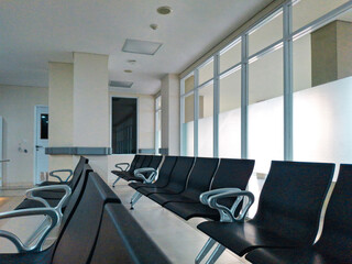 Empty waiting room in a modern hospital or clinic. Rows of clean chairs in a sterile lobby. Background for healthcare, medical services, or patient insurance concepts
