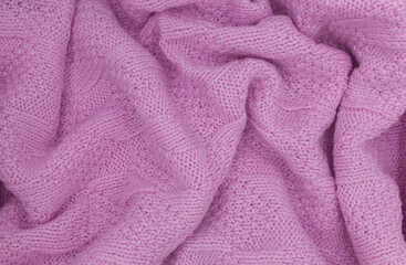 Pink knitted wool texture. Wool knit fabric. Knitted background. Crinkled wool knit texture. Pink knitted background. The fabric is knitted from wool yarn. 