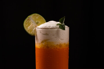 A fresh ice cold orange with milk cream on top with black background