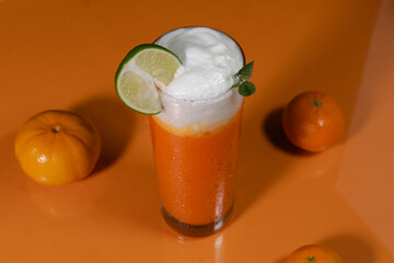 A fresh orange smoothie standing on orange table