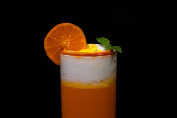 A fresh ice cold orange with milk cream on top with black background