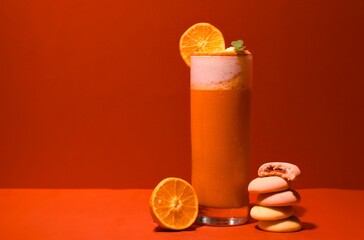 A fresh orange smoothie standing on orange background