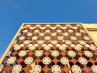 Low angle view of an architectural facade with a traditional, ornate floral repeating pattern....