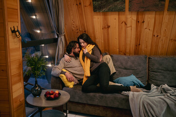 Cozy evening on the couch with a warm blanket and a loved one in a wooden cabin