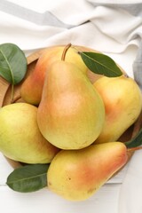 Fresh ripe pears and green leaves on white wooden table, flat lay