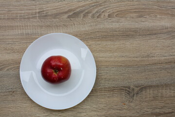 a large red home-grown apple from my own garden on a plate on the table