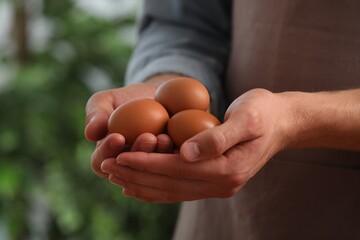 Man with many raw chicken eggs outdoors, closeup