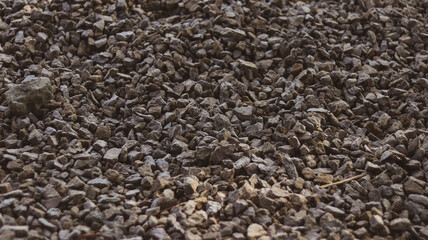 Close-up of compact gravel surface with mixed stone colors and rough texture. Ideal for construction, landscaping, groundwork, and material background themes.