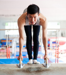 Male athlete doing complicated exciting trick on pommel horse in professional gym