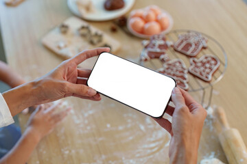 Baking. Hands holding smartphone while preparing cookies in a cozy kitchen.
