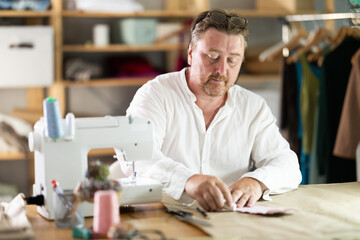 Middle-aged male dressmaker drawing detail on paper with chalk