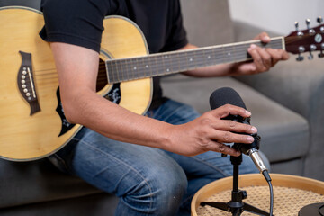 A young man practices guitar at home while taking an online music lesson, showing creativity and passion for learning.
