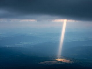 darkness. Beam of sunlight breaking through dark storm clouds, illuminating the ground. travel magazines, destination branding, designed for outdoor magazines and nature guides.