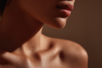 Smooth skin close up of female neck jawline and collarbone in warm light modern minimalist studio photo healthy complexion natural beauty serene mood