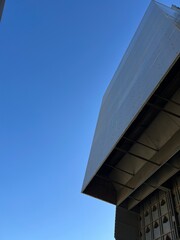 Modern angular building with metal facade against clear blue sky, architectural minimalism and geometric lines