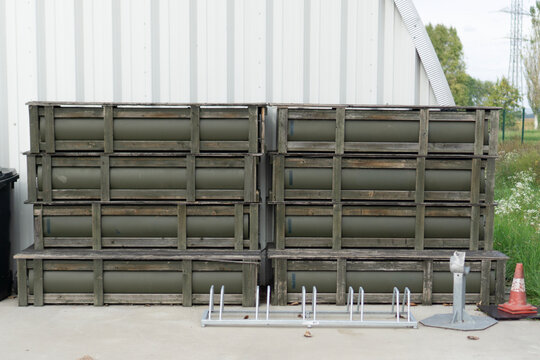 stack of military wooden crates for ammunition or missiles with protective green inserts standing outdoors near a building, concept of military warehouse, logistics, armament