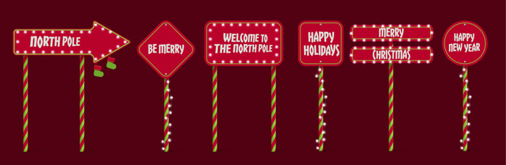 North pole sign set with festive red boards and candy cane posts - arrow direction, welcome message and holiday greetings for Christmas or winter celebrations. Illuminated borders on striped supports.