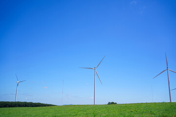 Fototapeta premium Wind turbines generating renewable energy under clear blue sky, symbol of sustainability, clean power, green technology, and environmental conservation for a better future.