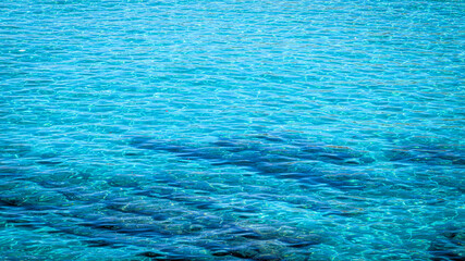 Vertical photo of crystal clear turquoise sea water revealing rocks and textures on the seabed. Captured in bright sunlight showing the beauty of the Mediterranean coast and the natural clarity of the