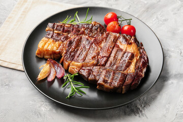 Delicious grilled beef steak with rosemary, onion and tomatoes on grey textured table, closeup