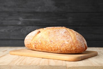 Loaf of fresh bread on light wooden table, closeup