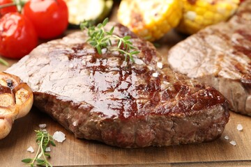 Delicious grilled beef steak with microgreens and vegetables on wooden board, closeup