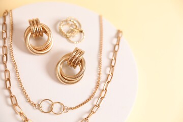 Beautiful gold jewelry on beige background, top view