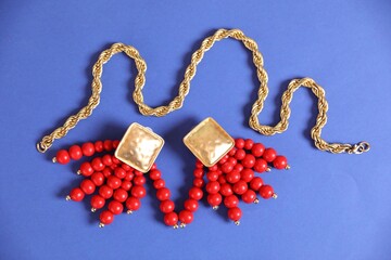 Beautiful gold jewelry on blue background, flat lay