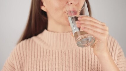 Close-up of an unrecognizable smiling woman holding a capsule and a glass of water, swallowing the vitamin. Concept of self care, prevention and healthcare