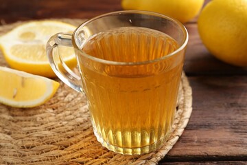 Aromatic tea in cup with lemons on wooden table, closeup