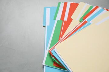 Many documents in folders on grey table, top view. Space for text