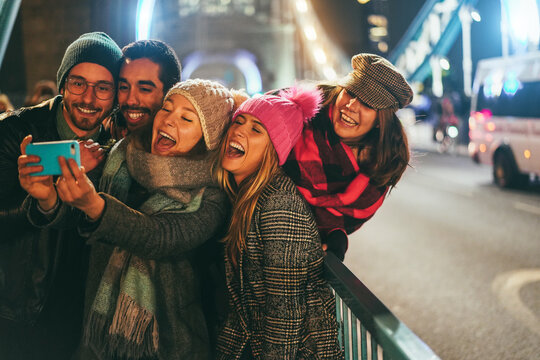 Happy friends having fun during winter season - Young people walking around city at night time - Party, fun, travel and tourist concept - Main focus on left girl face