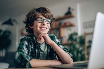 Smiling Boy with Glasses Using Laptop at Home for Remote Learning.