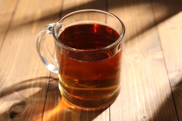Aromatic black tea in cup on wooden table, closeup