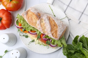 Delicious ciabatta sandwich with prosciutto, cheese and vegetables on white tiled table, flat lay