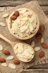 Fresh almond flakes and whole nuts on wooden table, flat lay