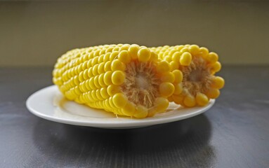 Two hot yellow corn cobs on white plate with steam on dark table, organic sweet maize vegetable food close-up, natural homemade meal concept