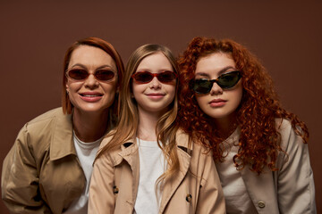Obraz premium Three generations share smiles in stylish autumn attire with vibrant red hair