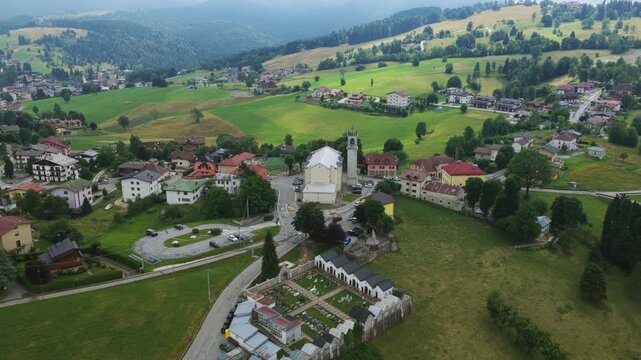 Tresch&egrave; Conca village in Roana, church, houses, and green mountain landscape in Italian Alps, Italy. Aerial drone