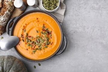 Delicious pumpkin soup served on grey table, flat lay. Space for text