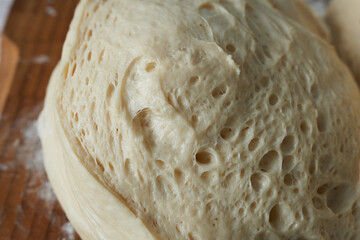Raw dough on a wooden board, close-up photo.